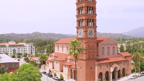 rising drone aerial footage, of st andrew catholic church clock bells tower landmark of pasadena city california with street traffic