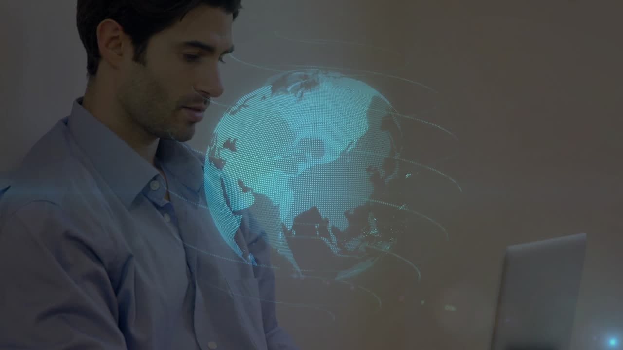 Mid-adult man typing on laptop in technology office, driving holographic globe showing data streams