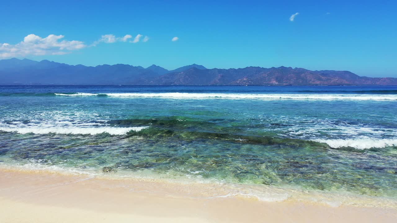 파도 배경이 있는 추상 열대 바다, 배경에 산, 아래로 기울면 모래 해변이 드러납니다.
