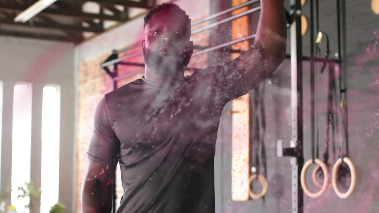 Male trainer standing gym while pink powder dispersing, reaching and gripping rig preparing workout