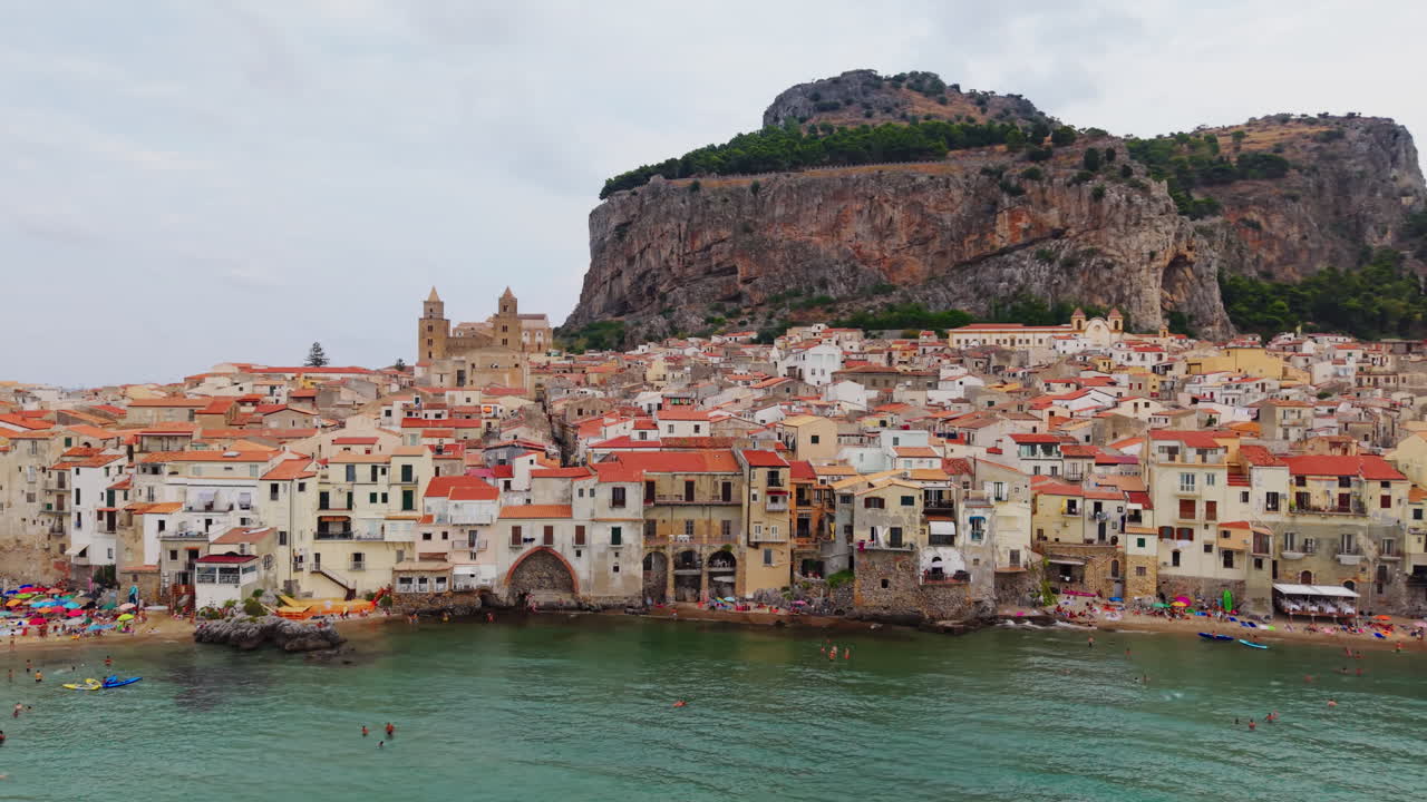 Cefalù's scenic coast with busy beach and historic town view
