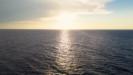 drone ascends above the ripples of the ocean during sunset with serene waters and soft reflections of evening light