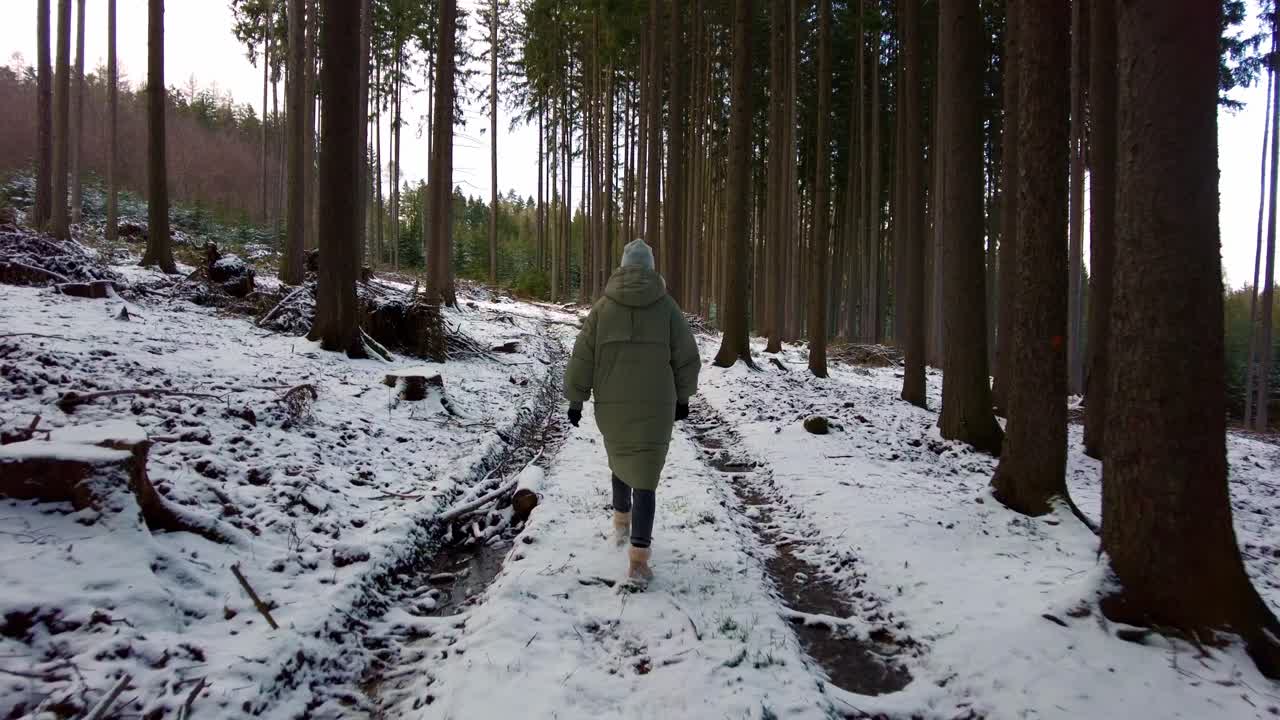 siguiente toma de una excursionista caminando por un camino forestal cubierto de nieve blanca durante la noche