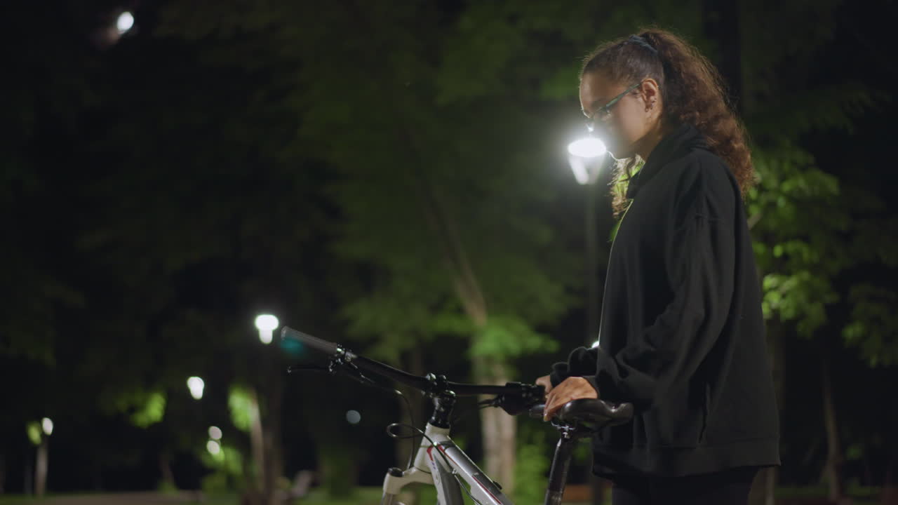 Night Cyclist Departure, Cyclist Prepares To Start Journey, Nighttime Scene Of Rider Poised For Departure Near Lamplight, Cyclist Stands Prepared To Begin Ride Alongside Illuminated Pathway At Night
