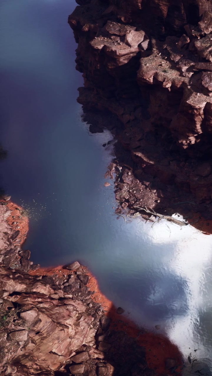 L'acqua scorre tra le rocce in un canyon sotto la luce solare intensa in un cielo sereno