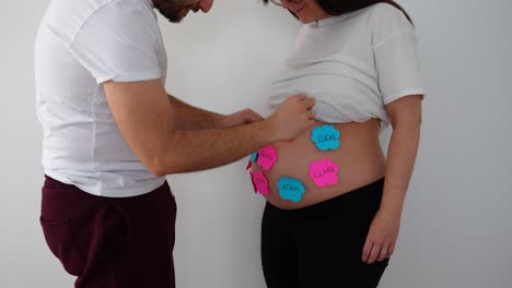 father removes sticky notes with boy names from pregnant belly revealing it’s a girl