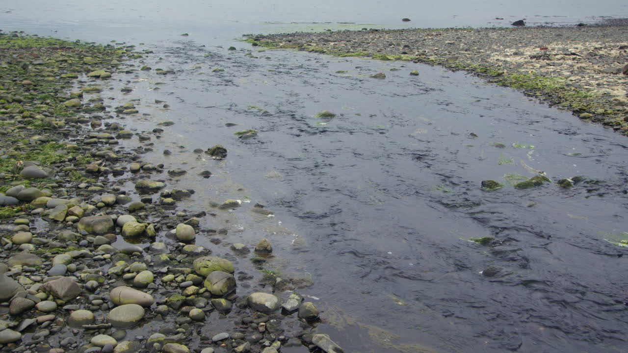 Wide shot of Milton burn stream flowing into luce bay, on Stairhaven Beach, Newton Stewart