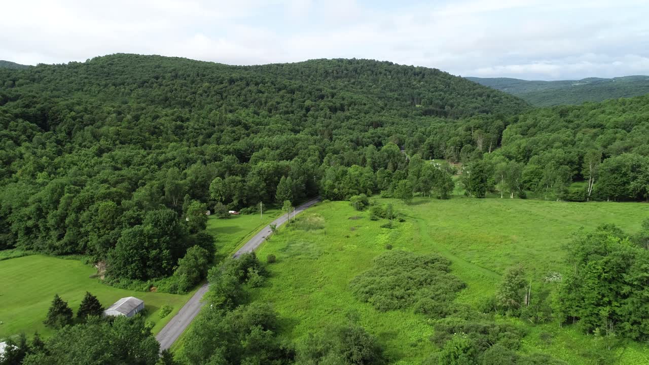 un coche rueda por una carretera hacia las montañas superpuestas en el paisaje de las montañas catskill cerca de walton nueva york