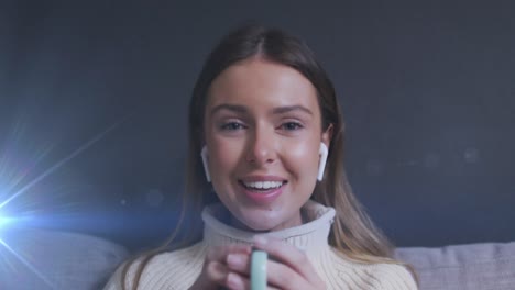 animación de puntos de luz sobre una mujer caucásica sonriente bebiendo café y haciendo una llamada de video en casa