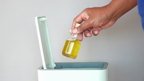 disposing of small bottle of liquid into trash can
