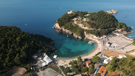 Aerial-static-high-angle-overview-of-secluded-cove-as-ocean-waves-rippl-on-surface-and-cars-drive-to-park-in-lot