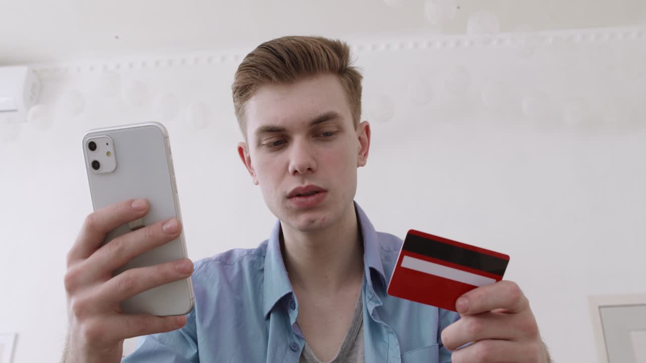 молодой человек делает онлайн-покупку с помощью мобильного телефона и кредитной карты