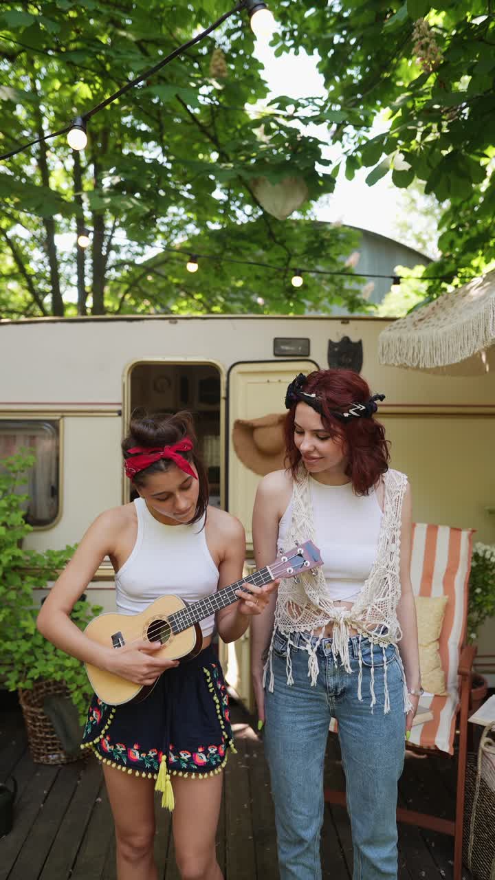 Due amiche che suonano l'ukulele all'aperto