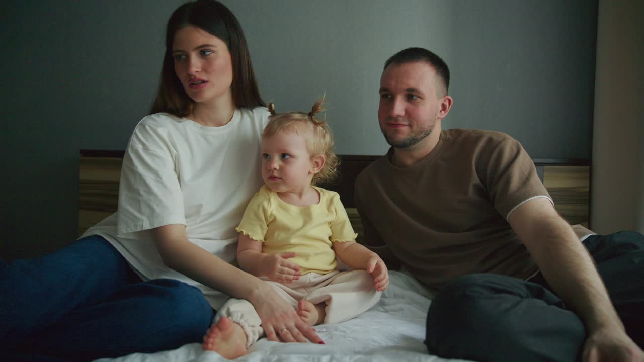 Famiglia felice con il bambino che gattona sul letto in camera da letto