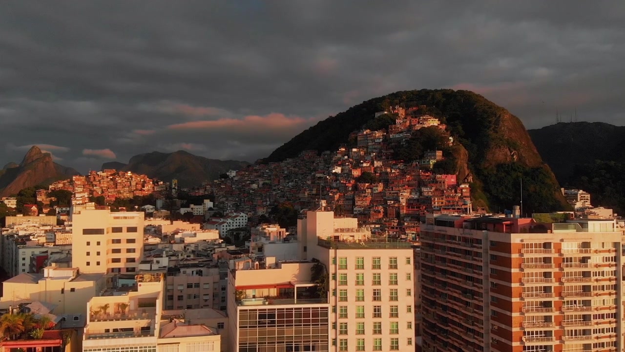 Favela sobe encosta rochosa acima do horizonte do Rio de Janeiro sob nuvens de tempestade