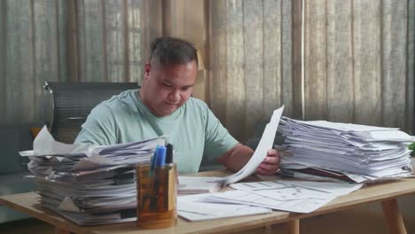smiling fat asian man enjoys working with documents at the office