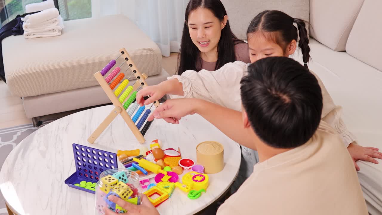 家庭学習のために、居心地の良いリビングで一緒に知育ボードゲームで遊ぶ幸せな家族。