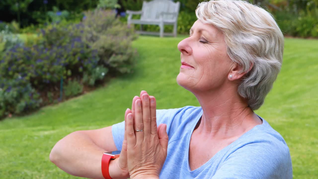 Ältere Frau macht Yoga im Garten