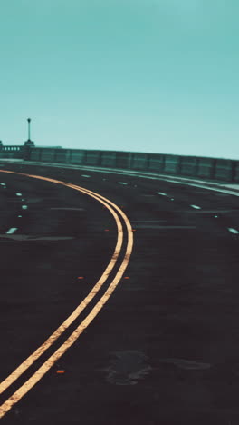 empty road on a bridge curving towards the horizon