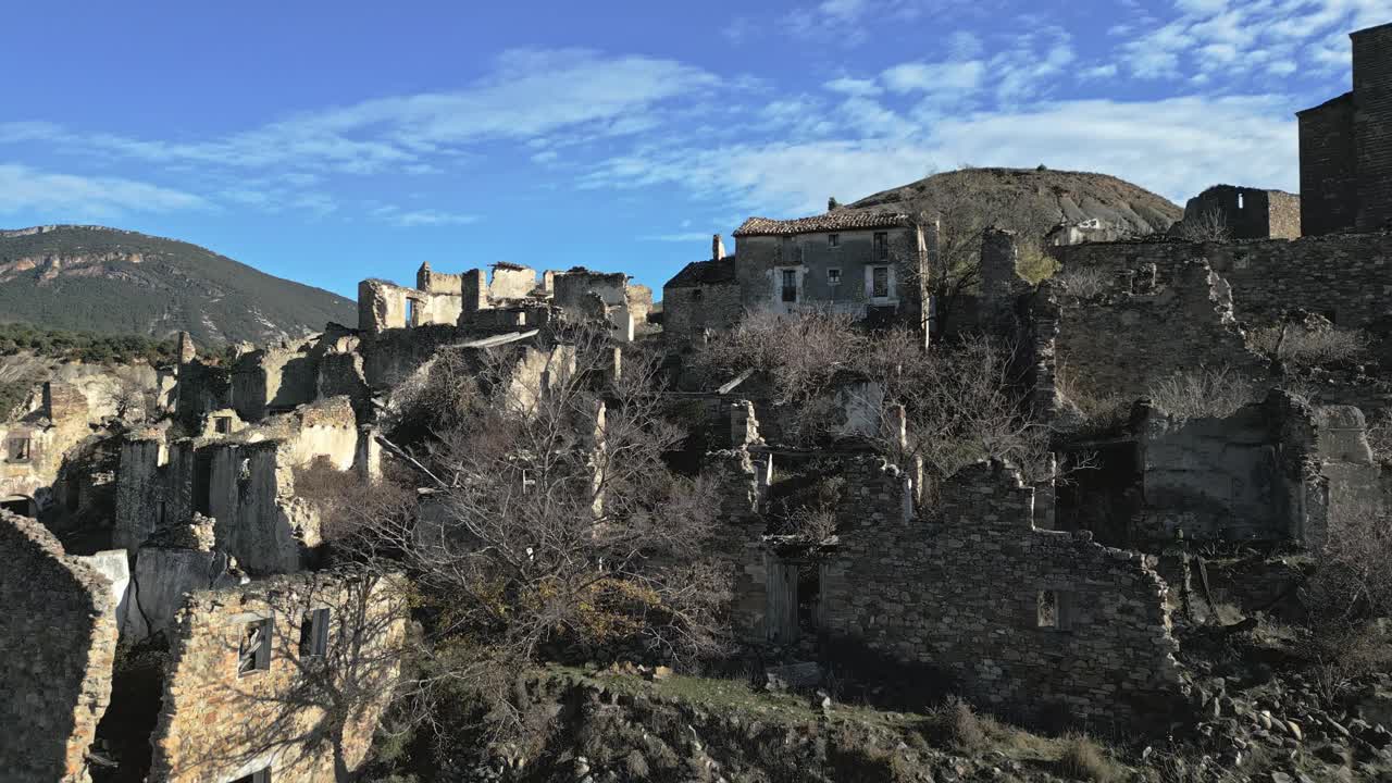 Edifici in pietra in rovina della storica città fantasma di Esco, un villaggio abbandonato in Aragona, Spagna, situato su una collina sotto un cielo blu con alcune nuvole in una giornata di sole