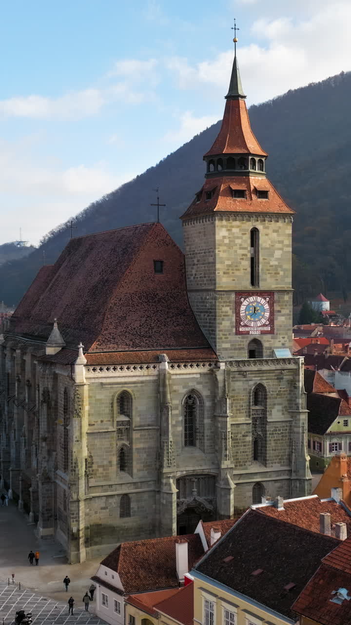 Aerial drone view of The Black Church in the city center of Brasov, Romania surrounded by mountains. Vertical