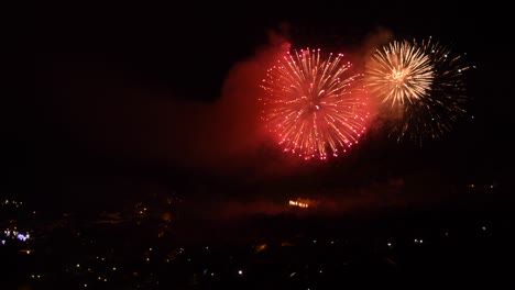 celebration with many colorful fireworks, over a mountain town, at night