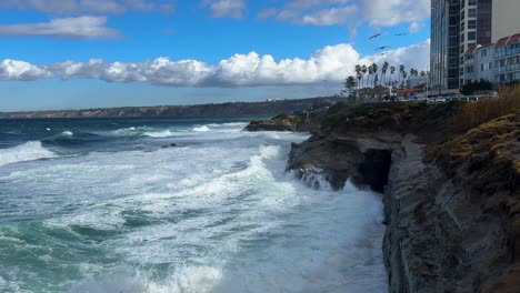 King-tide-at-La-Jolla-Cove-skyline-view-over-waves-crashing-on-clliffs-birds-flying-by.