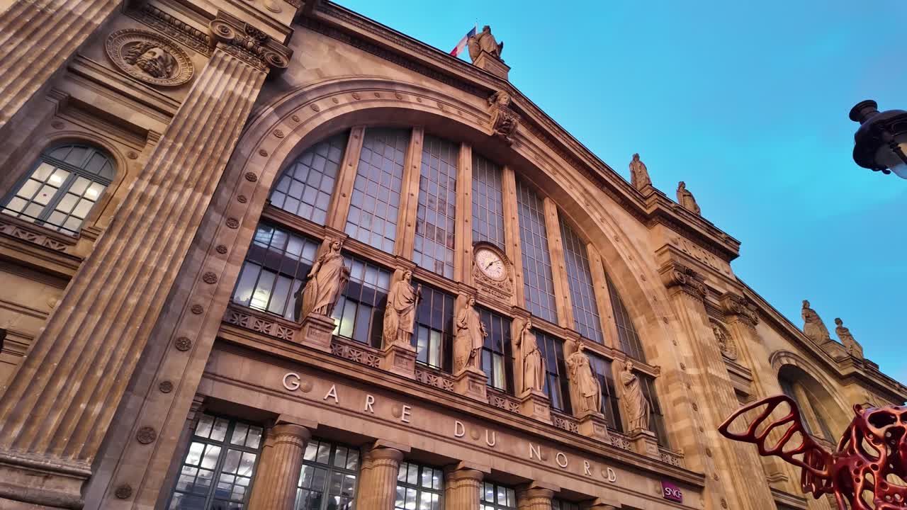 Gare du Nord mainline railway facade details with red winged bear statue in sunset, Paris, France. Looking down
