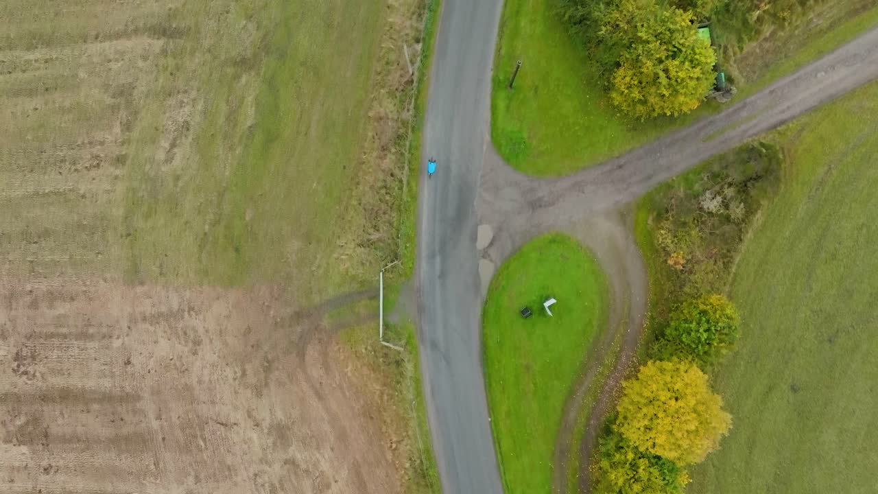 Aerial of cyclist on country road bike ride, high aerial cycling overhead shot