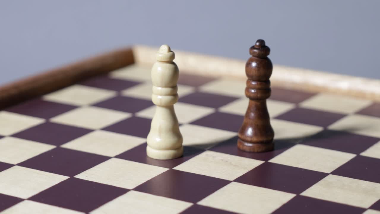 Cinematic shot rotating around black and white chess queens on a chessboard