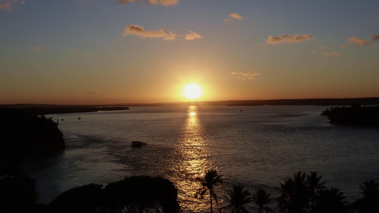 Dolly in aerial drone wide shot of the huge tropical Guara&iacute;ras Lagoon with a ferry boat in the famous beach town of Tibau do Sul during a golden colorful sunset near Pipa Brazil in Rio Grande do Norte