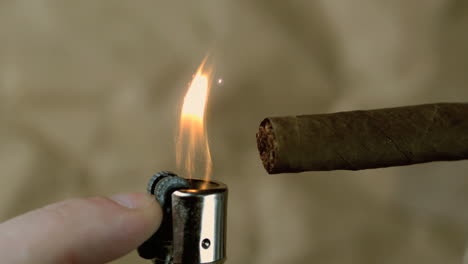 la mano encendiendo un cigarro sobre un fondo beige