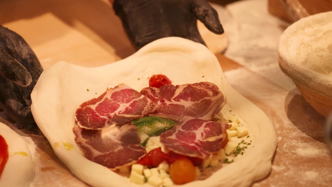 Chef che prepara pizza gourmet con salumi e verdure