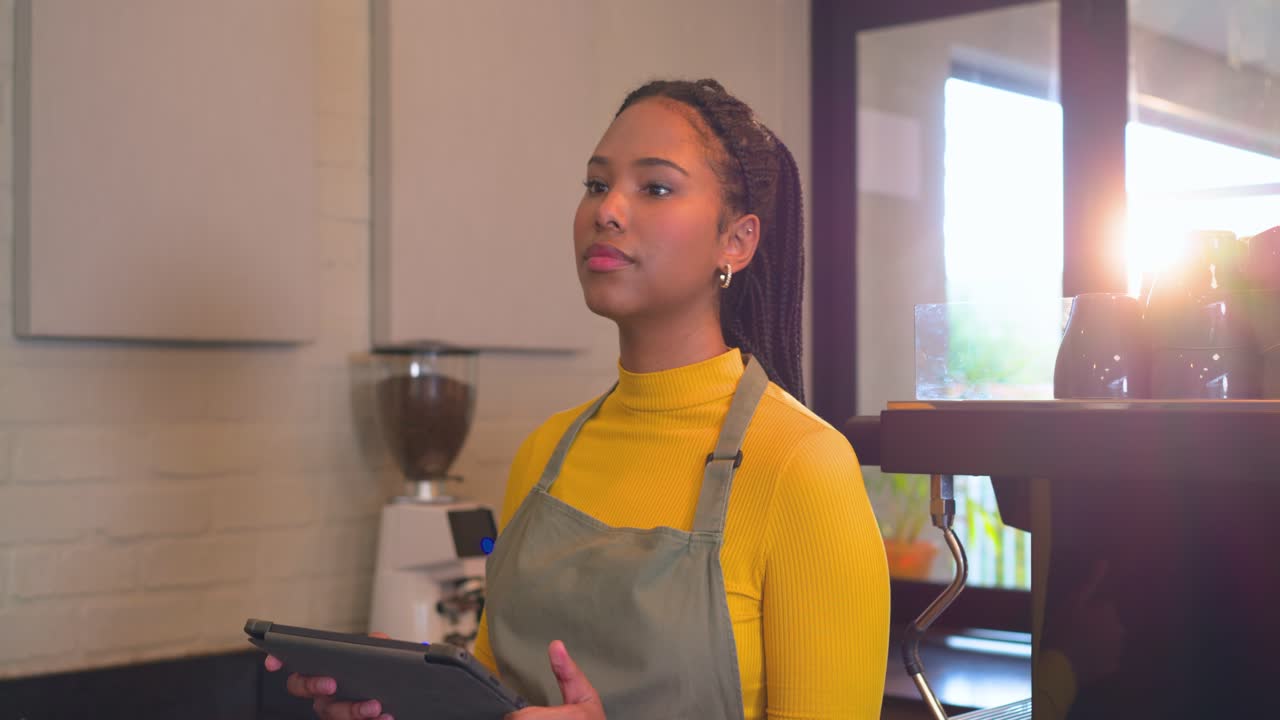 Avviso di ricezione ordine: barista sorridente che tiene in mano un tablet e tocca il registratore di cassa al bancone, rivolta verso il cliente