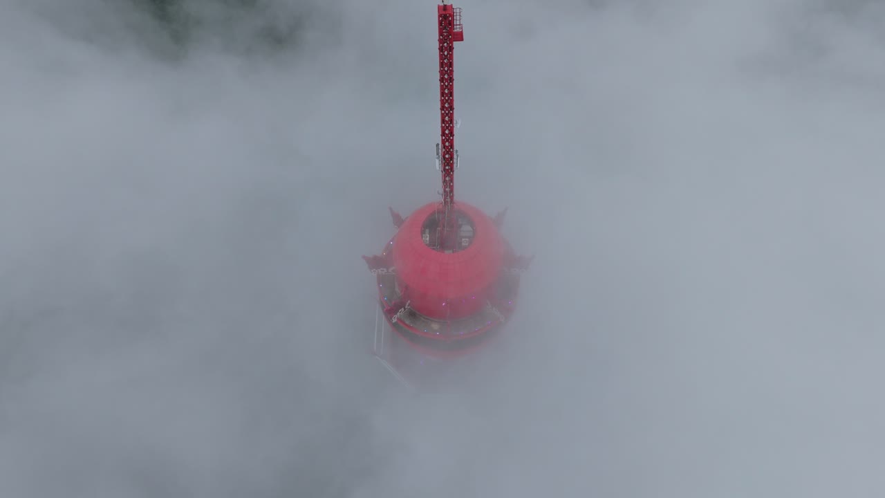 Torre di osservazione rossa che si erge sopra un mare di nuvole.