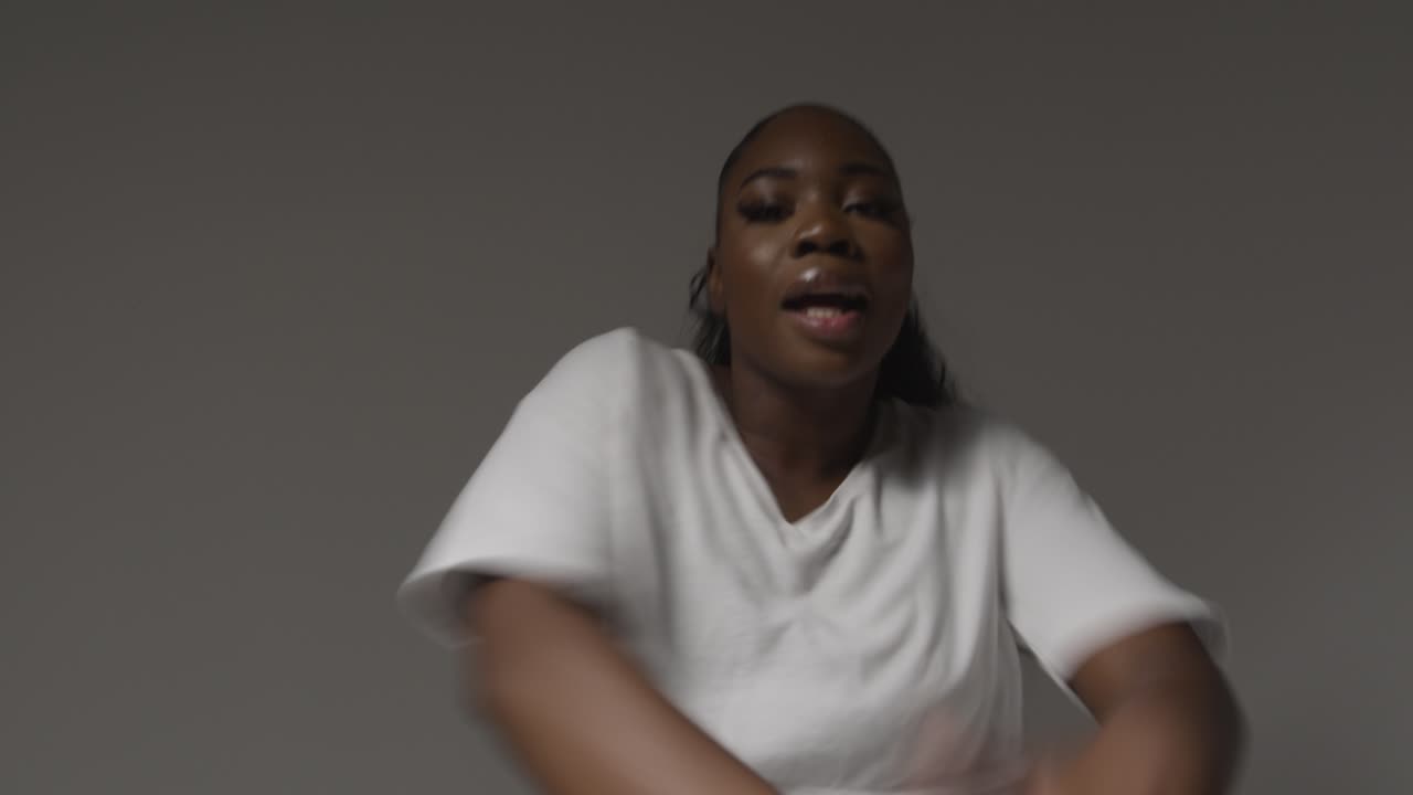 Studio Portrait Shot Of Young Woman Dancing With Low Key Lighting Against Grey Background 4