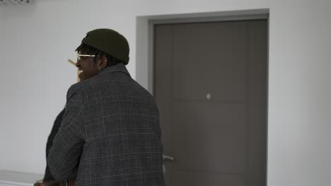 black man in front home door in trendy coat, leaving house