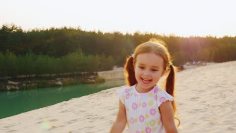 cheerful carefree girl three years running in the sand against the backdrop of the beautiful lakes a