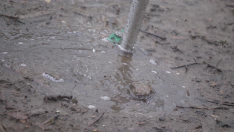 rain water falling into mud puddle ground stake slow motion