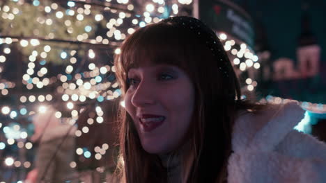 Close-of-of-a-beautiful-Woman's-Face-with-Dark-Hair-showing-disappointment-at-a-Christmas-Market-surrounded-by-flickering-Christmas-Lights