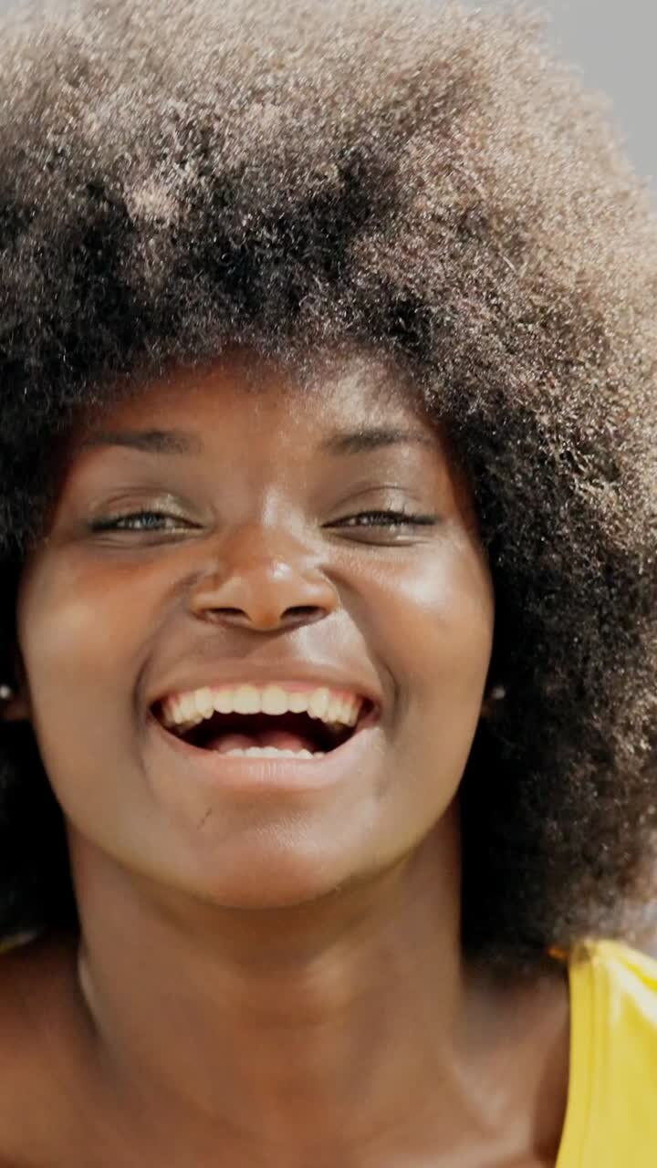 Close-up portrait of a happy young Black woman with an afro laughing