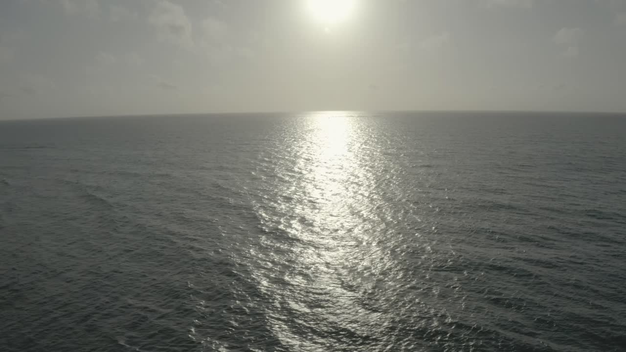 Aerial drone shot of the empty calm ocean with the morning sun high in the background. Kenya's indian ocean