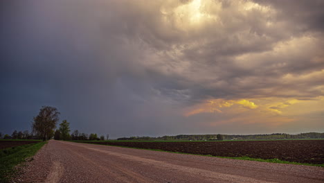 Statische-Aufnahme-Erstaunlicher-Gepflügter-Ackerflächen-Auf-Beiden-Seiten-Eines-Ländlichen-Weges-Mit-Vorbeiziehenden-Weißen-Wolken-Im-Zeitraffer-Am-Abend