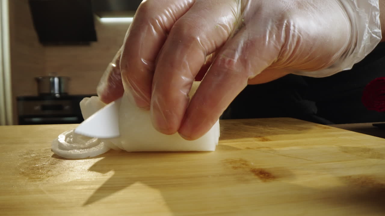 Primo piano di una mano che affetta una cipolla su un tagliere
