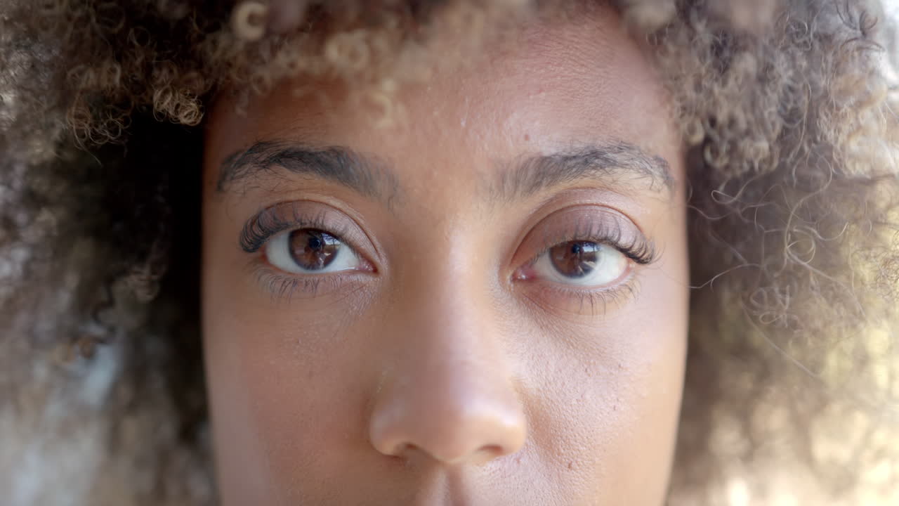 Close-up of woman's eyes with curly hair, focusing on facial expression