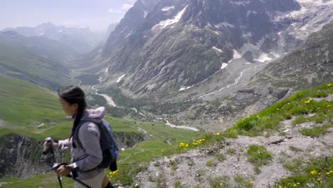 woman hiker descends on alpine forest trail on the tour du mont blanc, with hikers making their way through lush, green landscapes