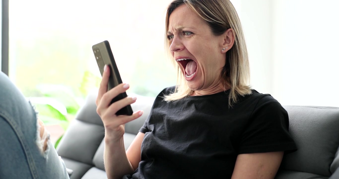 Mujer grita con ira mientras sostiene el teléfono durante una llamada