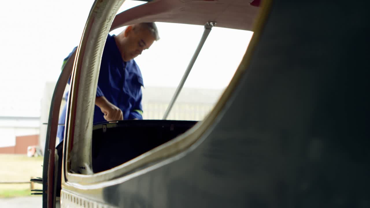 Ingegnere che ripara un aereo in un hangar 4k