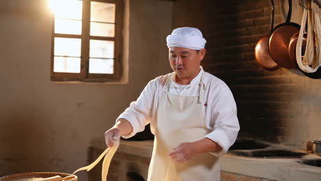 chef making noodles in a traditional kitchen