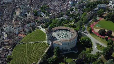 aerial orbit of munot circular fortification in verdant hill next to high rhine river and schaffhausen village between woods, switzerland